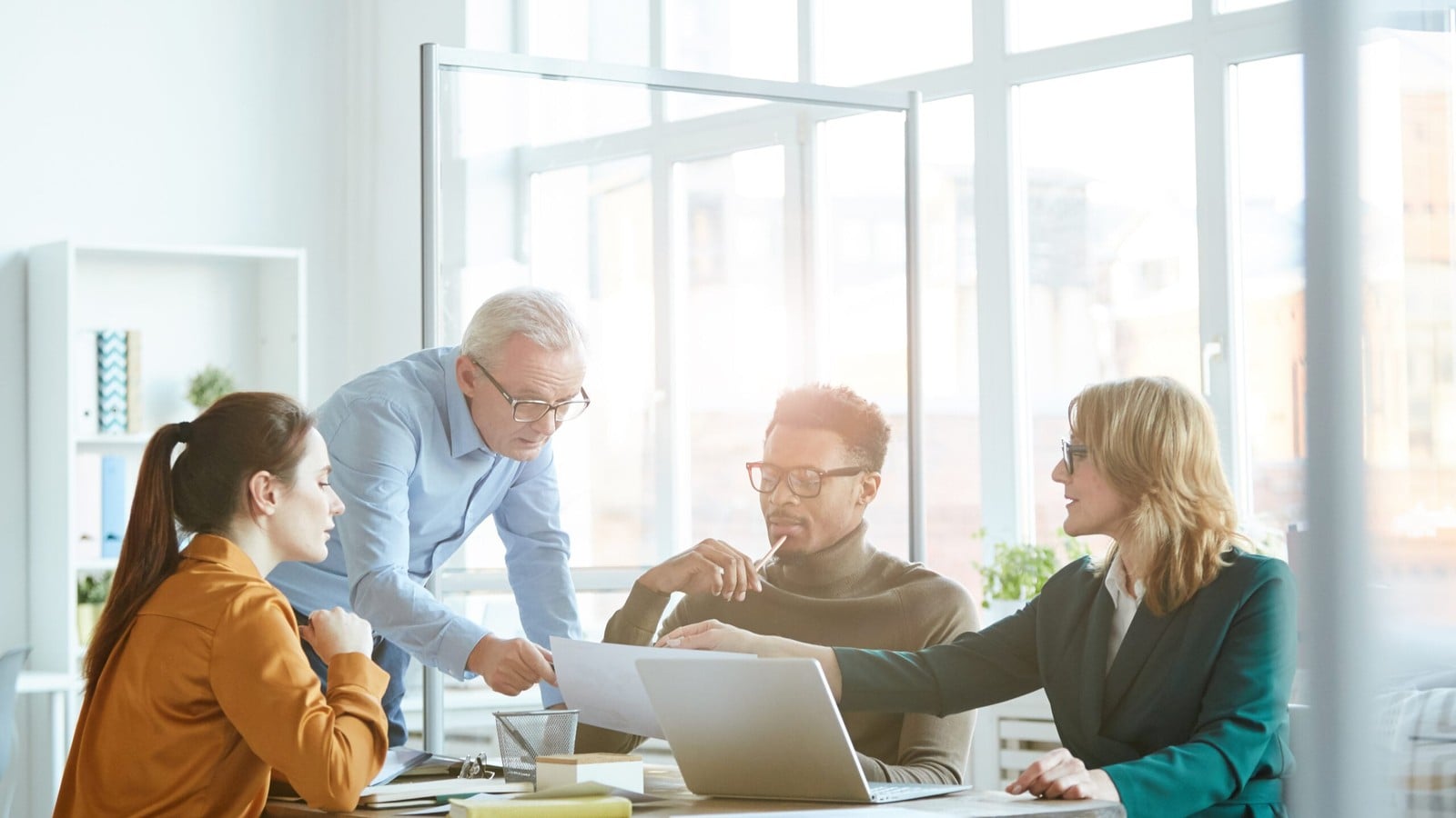 A team meeting around a table in a glass-walled office