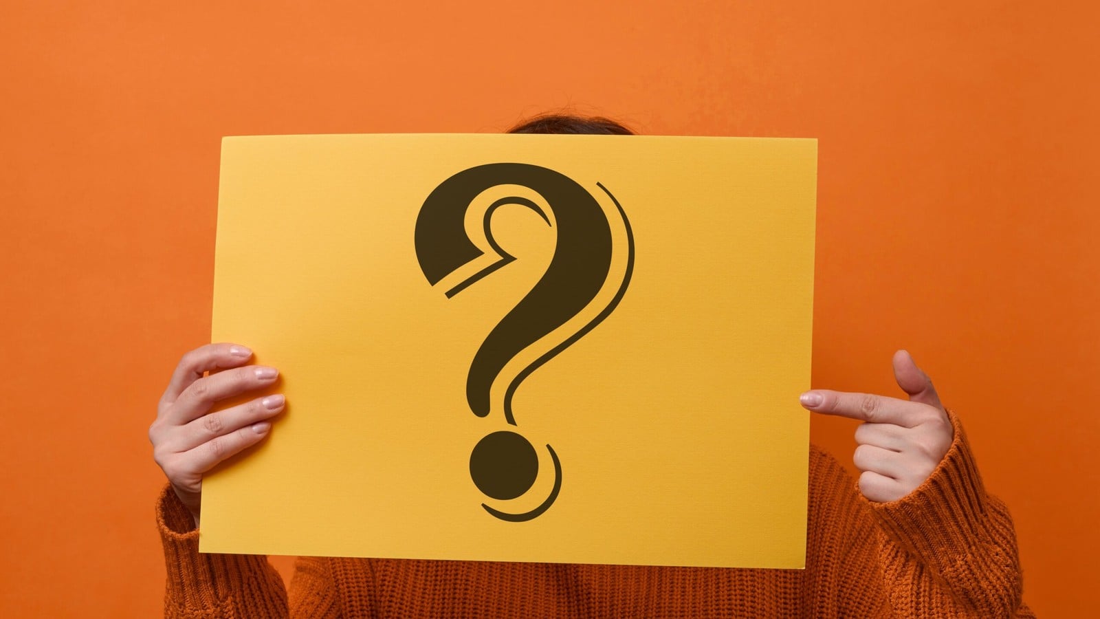 A person holding a yellow card with a large question mark