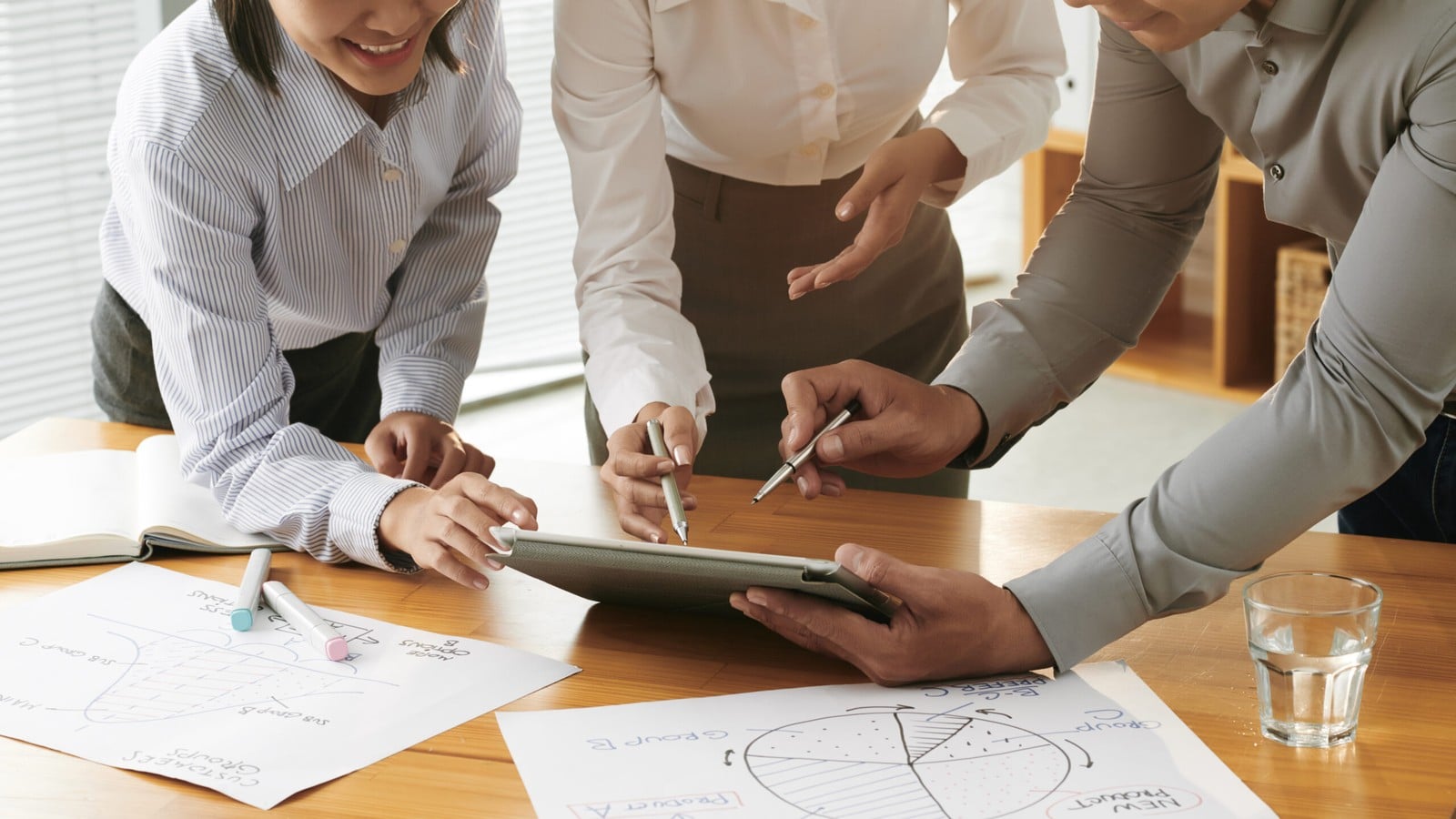 A team gathered around a table reviewing charts and a tablet