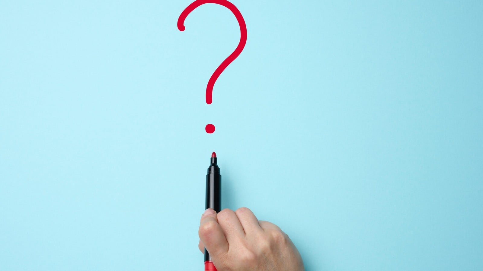 A red question mark drawn on paper beside a marker